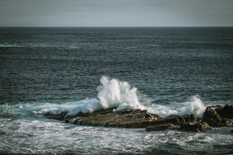 Ocean waves crashing against rocks with a clear sky